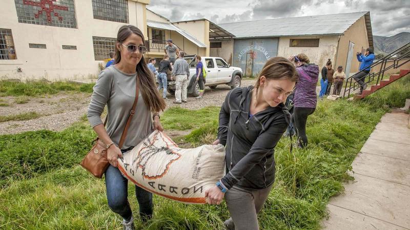 秘鲁的两名女性志愿者正在运送一袋袋大米.