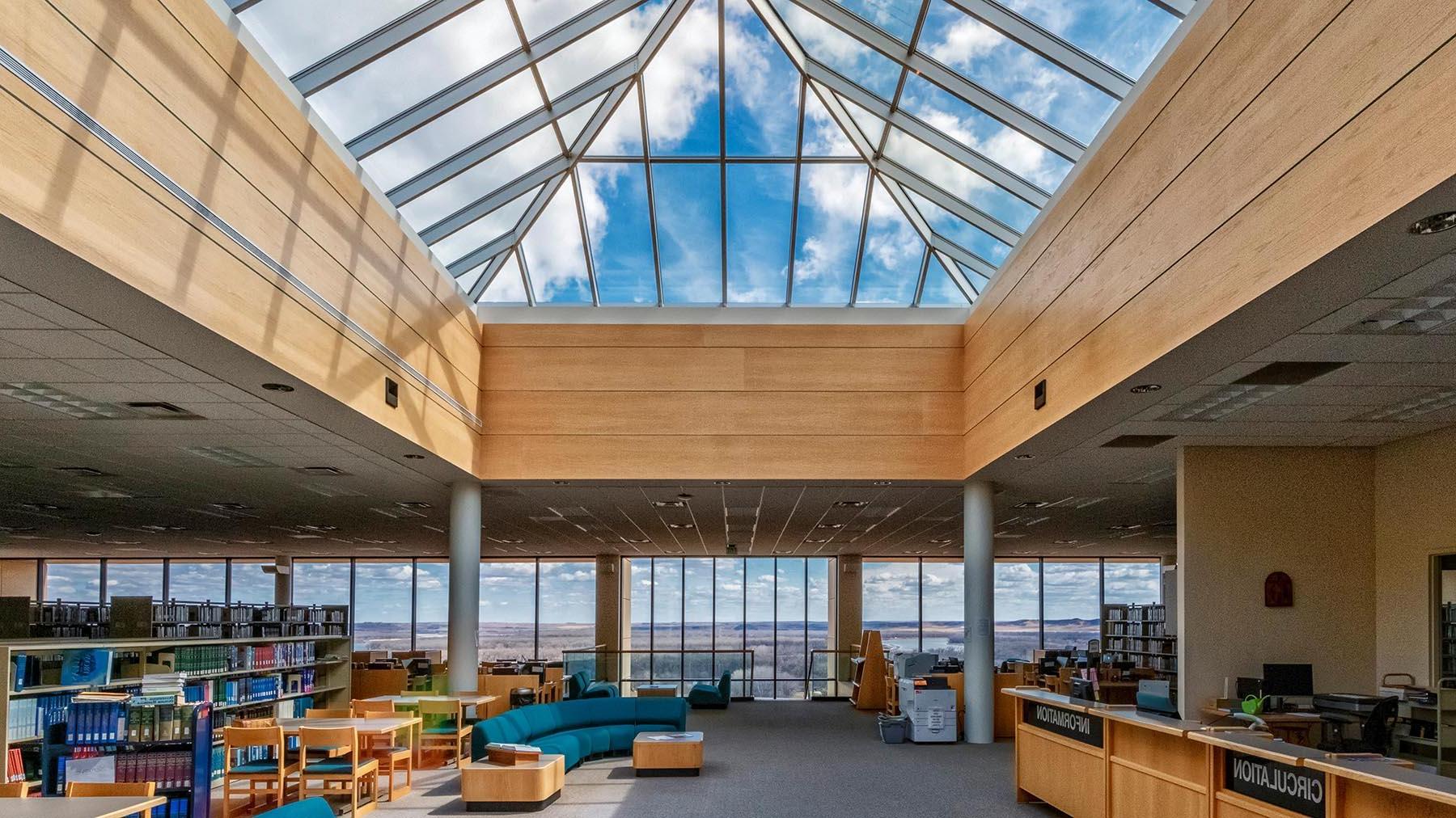 View of the library from the entrance, showcasing large skylight and west wall of windows looking out to Missouri River Valley